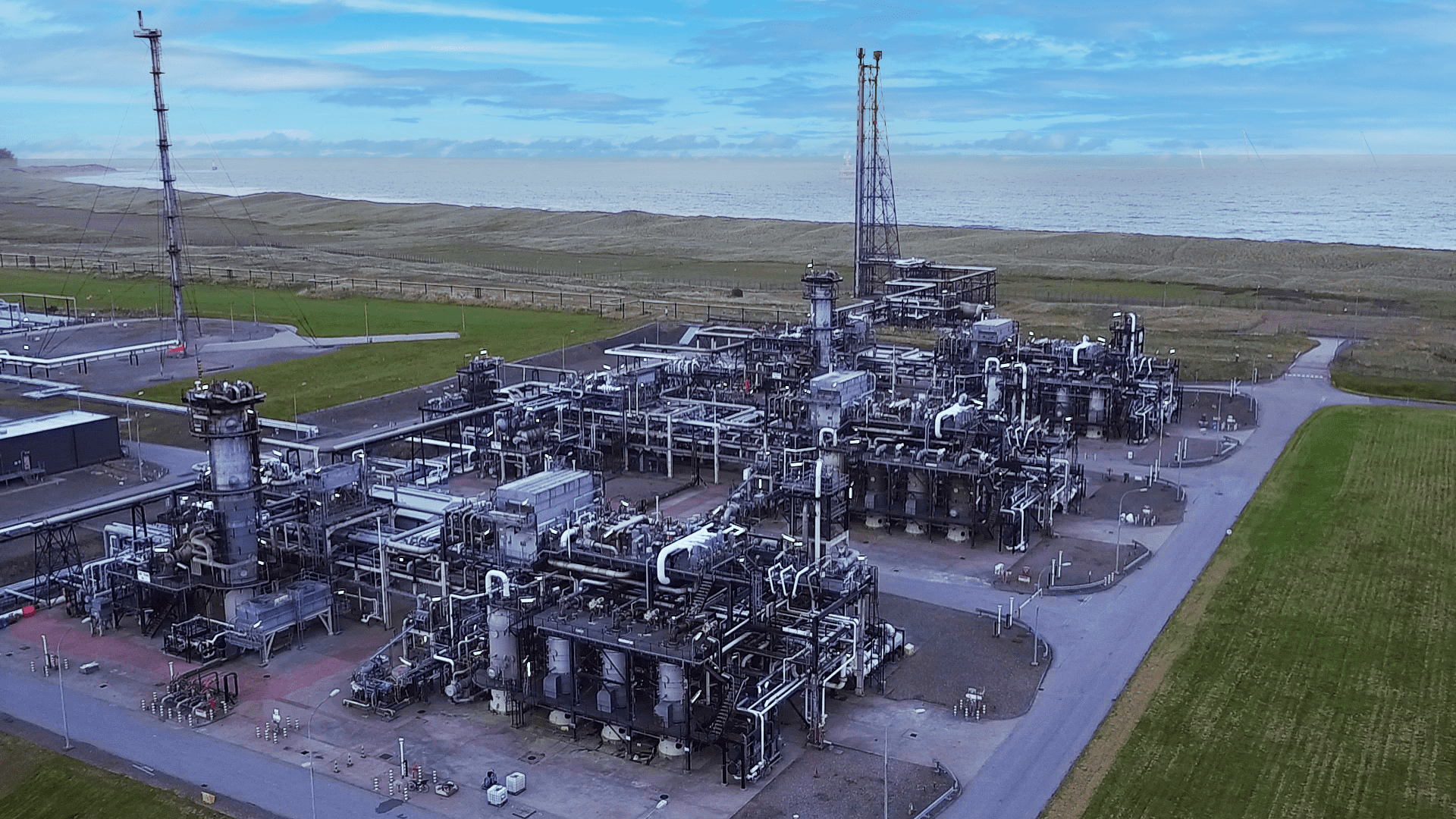 The image is of a large factory with many machines in St Fergus. It is an aerial view showing the factory surrounded by grass fields under a cloudy sky.
